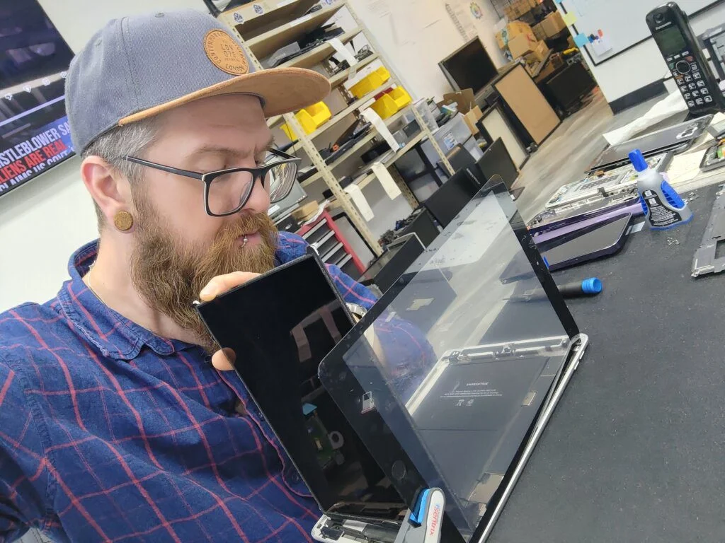 scott repairing ipad tablet screen and battery looking in opened up fixing tech device in shop 1