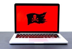MacBook Pro turned-on with ransomware jollyrogger flag on screen ready to clean up virus repair remote attack scammer for business or residential customer